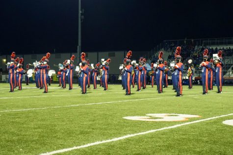 Marching band plays on football field at night