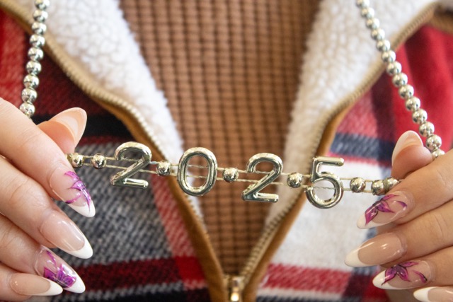A student photographed holding a necklace that reads ‘2025’ from New Years celebration.