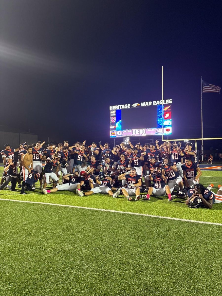 Football team huddles below the score board to celebrate their long awaited win.