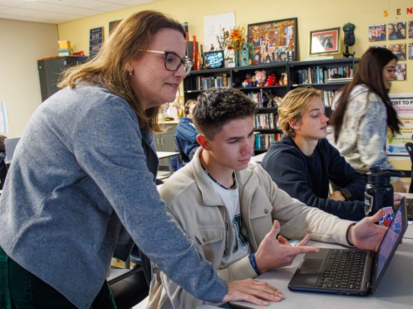 College Composition teacher coming to the aid of a student for a class assignment.